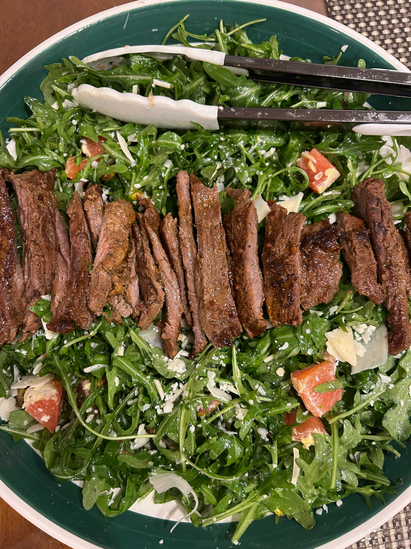 Arugula salad topped with steak